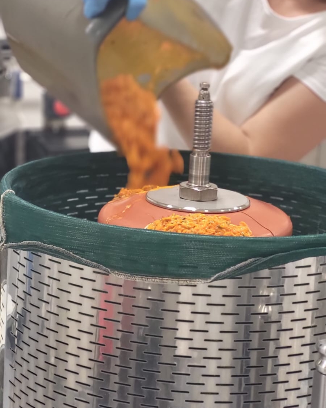 Technik drží kovovou svíčku na růžovém těle, v zeleném koši s oranžovým práškem.